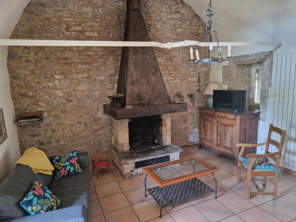 sala de estar con chimenea de piedra y mesa en La Maison du Berger, en La Cresse