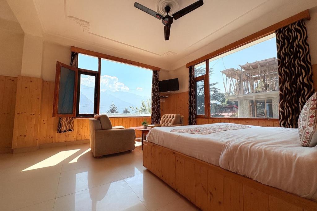 a bedroom with a bed and a chair and windows at The Suraj Cottage Manali ! Private Parking ! Bonfire ! Playing Zone ! Near Mall Road in Manāli