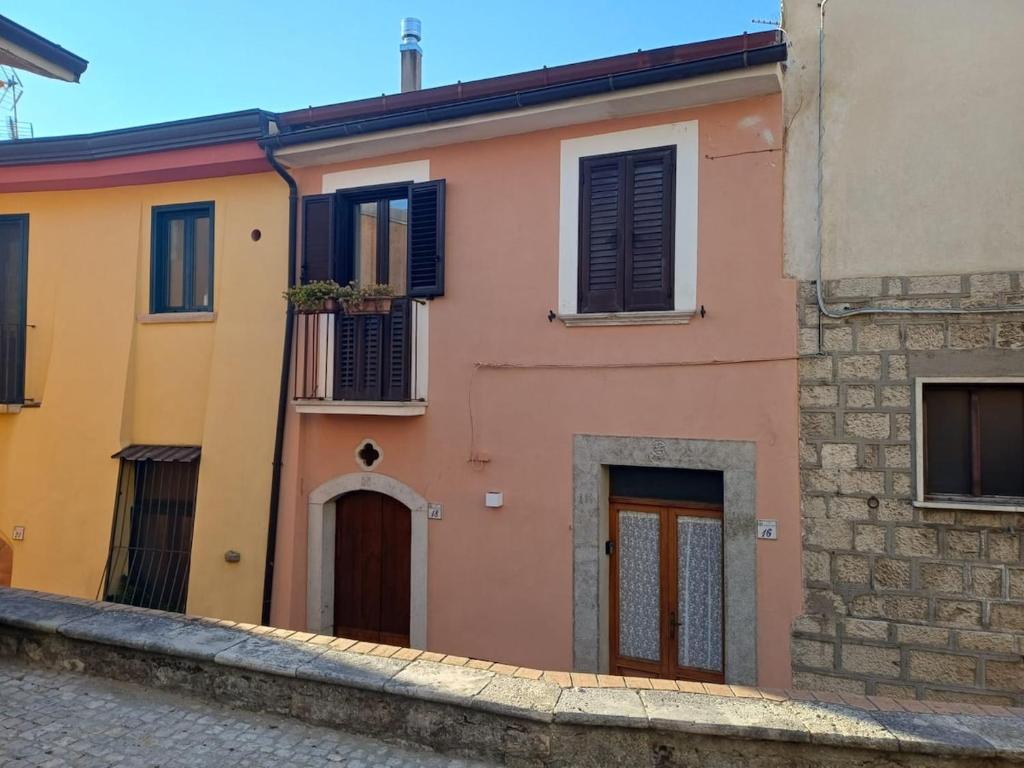 a pink and yellow house with a balcony at VicoloHOME in Fragneto lʼAbate