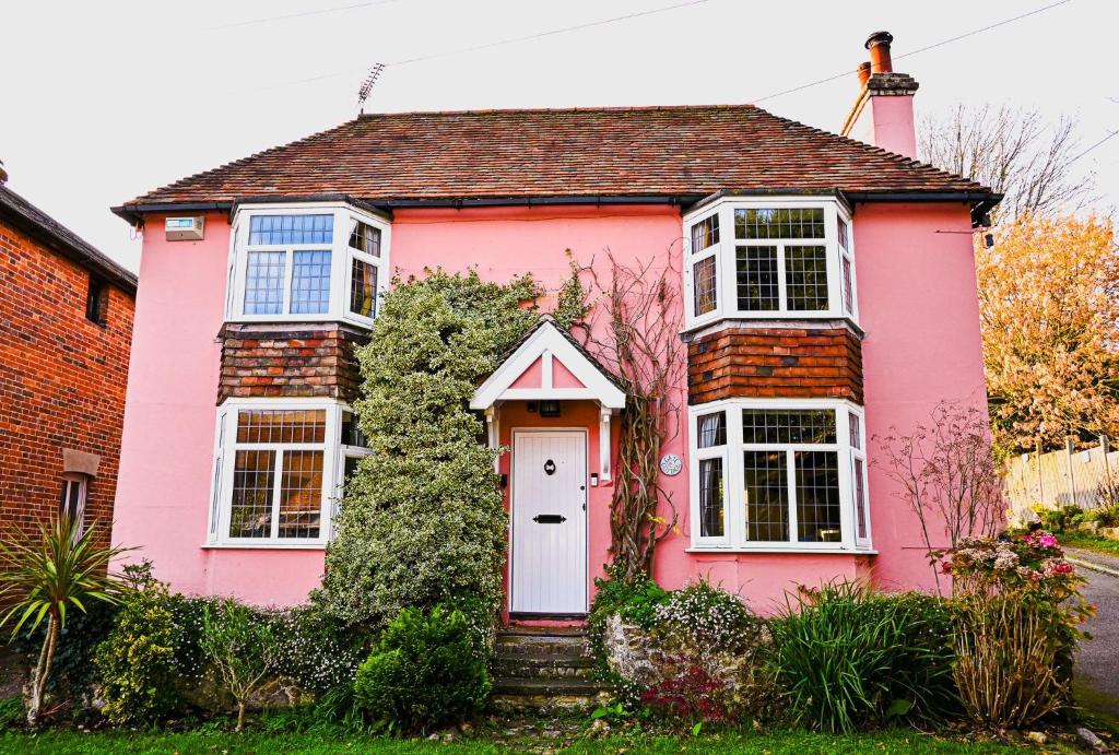 ein rosa Haus mit einer weißen Tür in der Unterkunft Gate Cottage, Saltwood Village in Sandling Junction