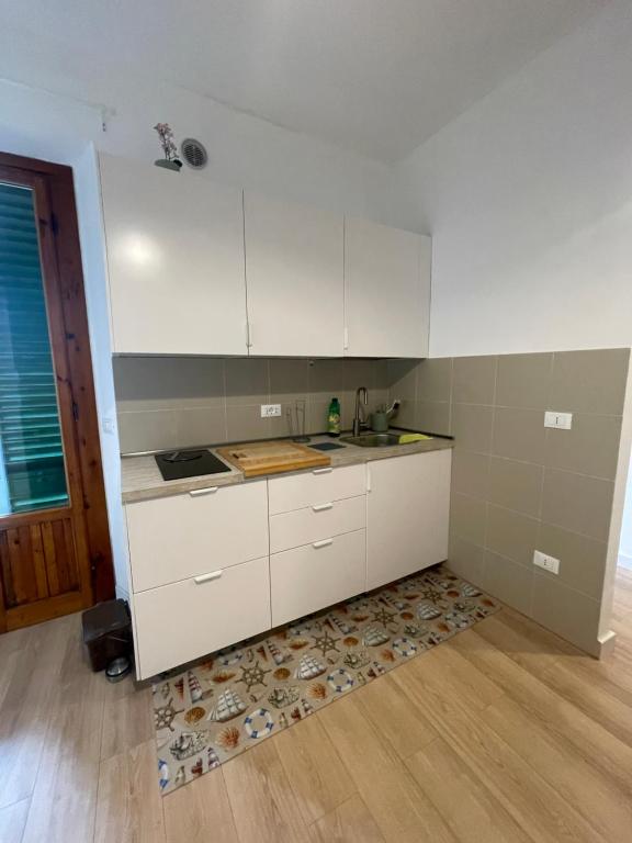 eine Küche mit weißen Schränken und einem Holzboden in der Unterkunft Casa Rosa in Montelupo Fiorentino