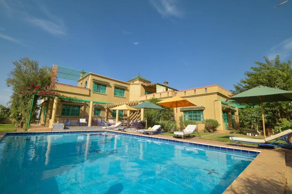 a large swimming pool with chairs and umbrellas at Bluegreen Guest House Marrakech in Aït Amara