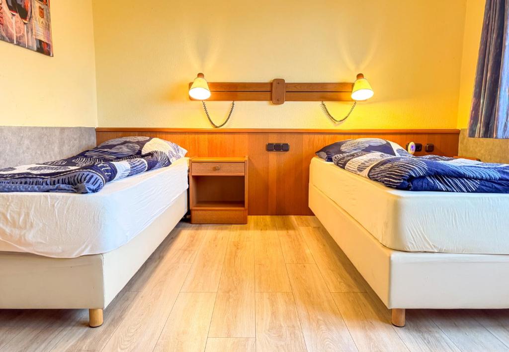 two twin beds in a room with wooden floors at 33 - 16 Hotelkamer voor twee personen in Bunkenburg