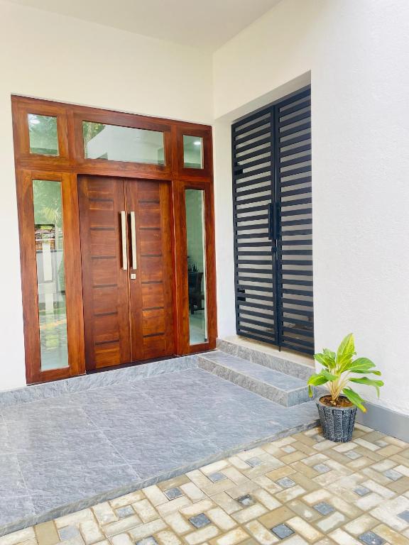 a wooden door of a house with a potted plant at THE ONE Villa in Weligama