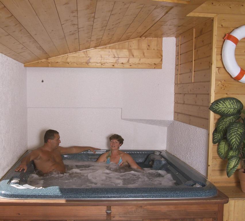 a man and a woman in a hot tub at Hôtel Les Côtes, Résidence Loisirs et Chalets in Morzine