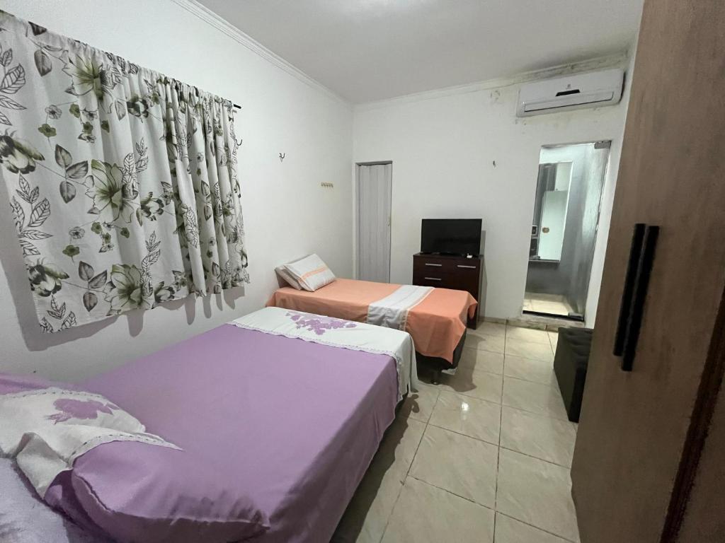 una camera d'albergo con due letti e una televisione di Green House a Belém