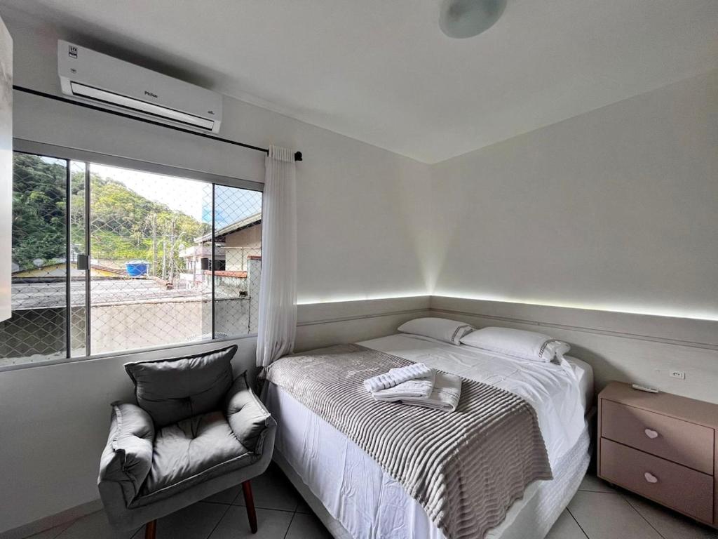 a bedroom with a bed and a chair and a window at Casa ampla e confortável em Balneário Camboriú in Balneário Camboriú