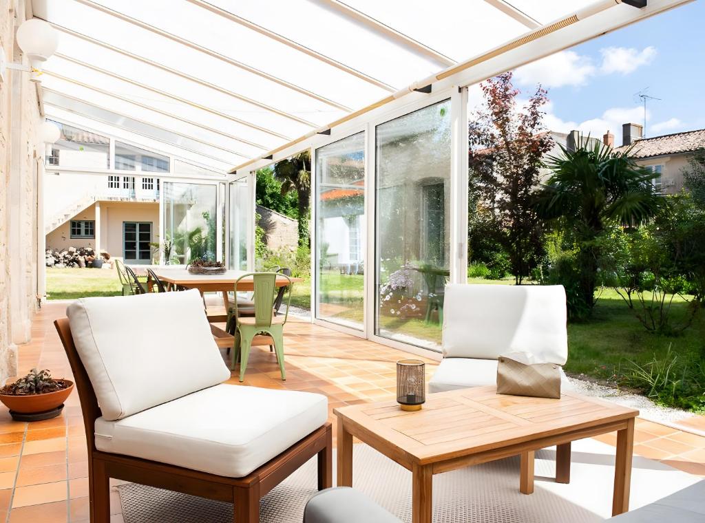 eine Terrasse mit einer weißen Pergola sowie einem Tisch und Stühlen in der Unterkunft La Maison De Famille in Luçon