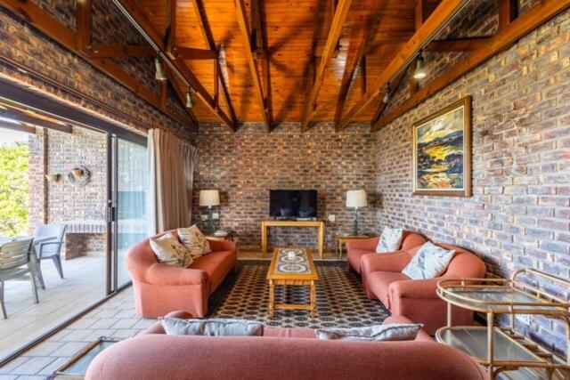 een woonkamer met banken en een bakstenen muur bij 8 Tarbet Ness in Vosburg