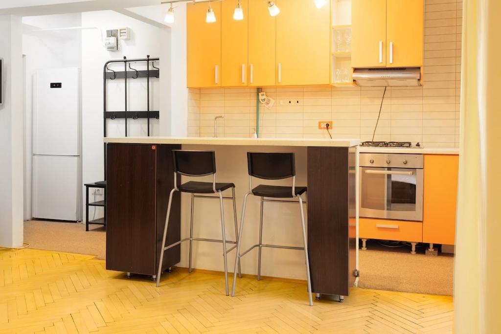 a kitchen with orange cabinets and a counter with stools at By the Park in Văleni