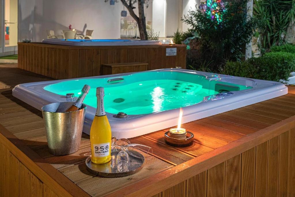 a hot tub sitting on a wooden table with a bottle of champagne at The Twin Boutique Hotel in Torre Suda