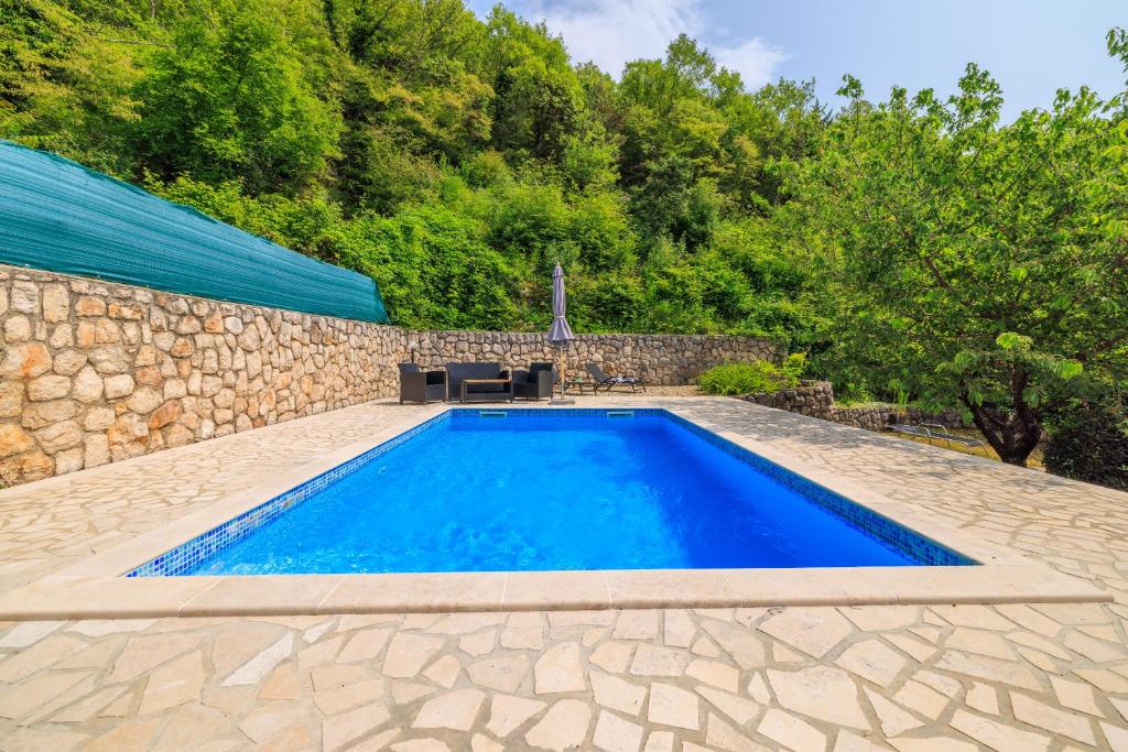 an image of a swimming pool with a stone wall at KUCA MARSSILI in Grižane