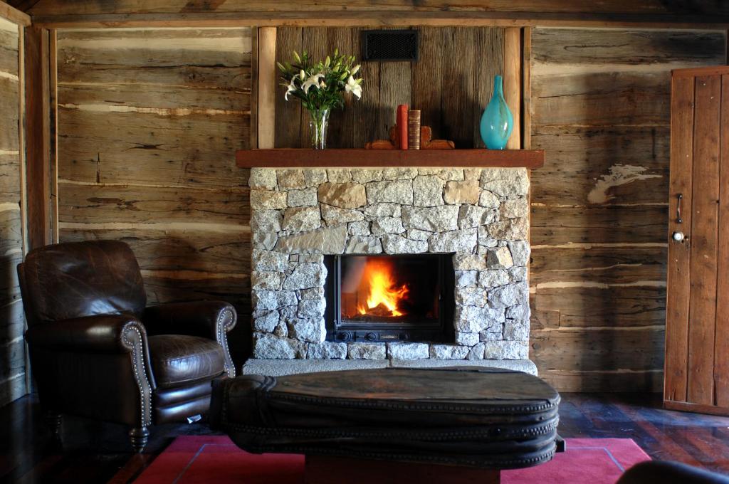 a living room with a stone fireplace and a chair at 1860 Luxury Accommodation in Beechworth