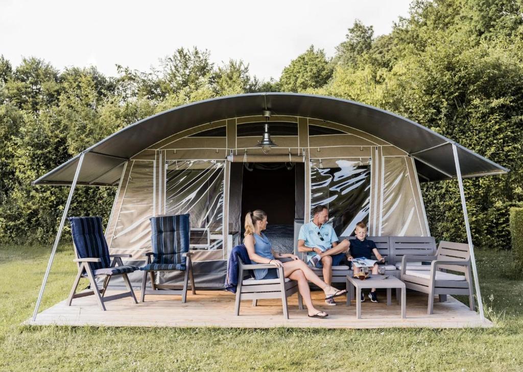 a family sitting in front of a dome tent at Domaine des Messires-Lodge de Luxe in Laveline-devant-Bruyères