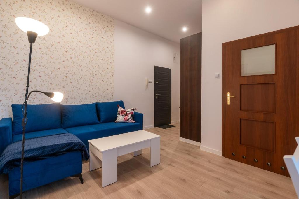 ein Wohnzimmer mit einem blauen Sofa und einem Tisch in der Unterkunft Mysłowice Urban Harmony Apartment by BookingHost in Mysłowice
