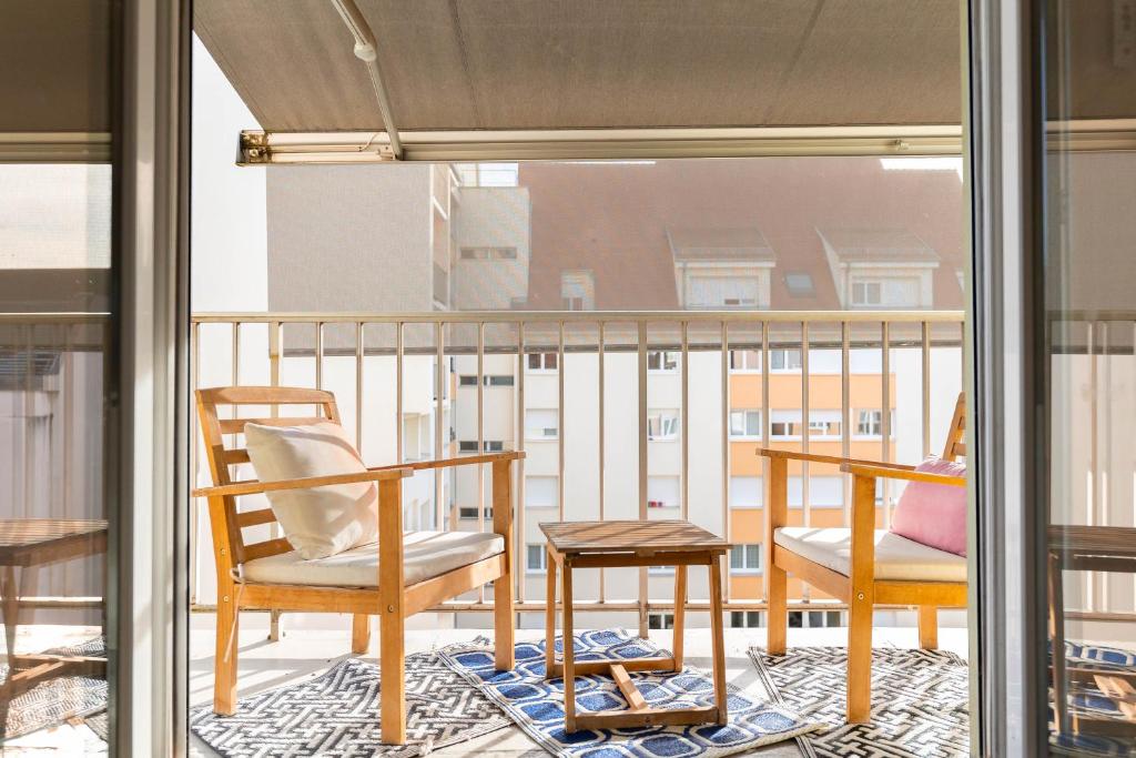 ein Balkon mit zwei Stühlen und einem Tisch in der Unterkunft Le 12 - City Center in Colmar