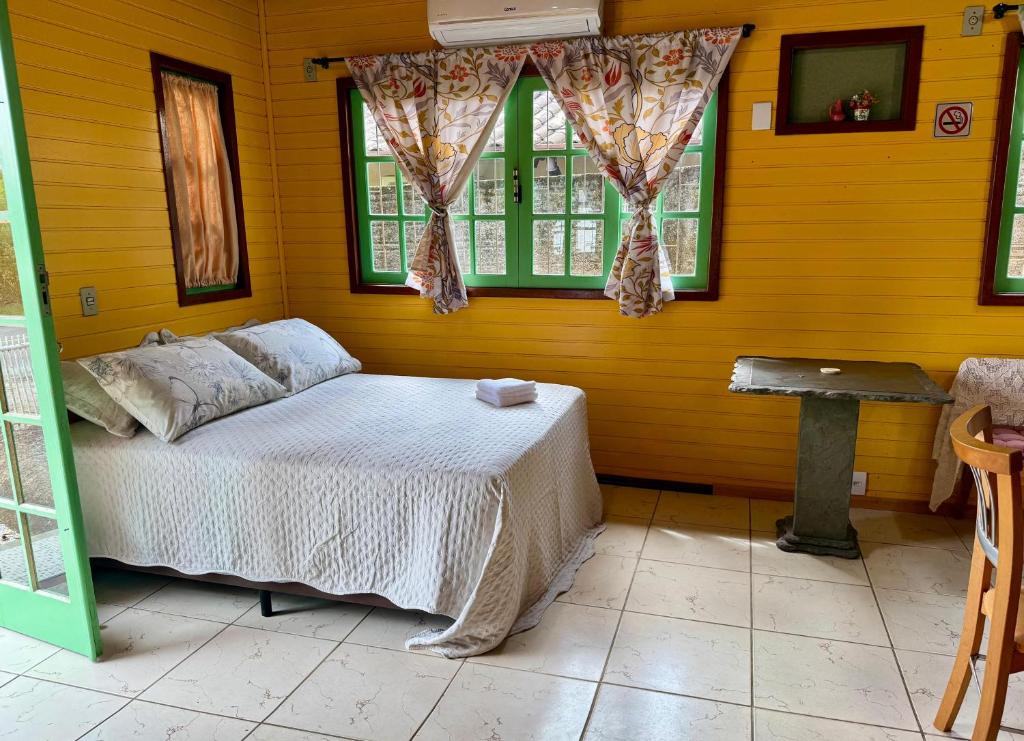 a bedroom with a bed and a window and a table at Complexo de Hospedagem e Gastronomia Café Cacupé in Florianópolis