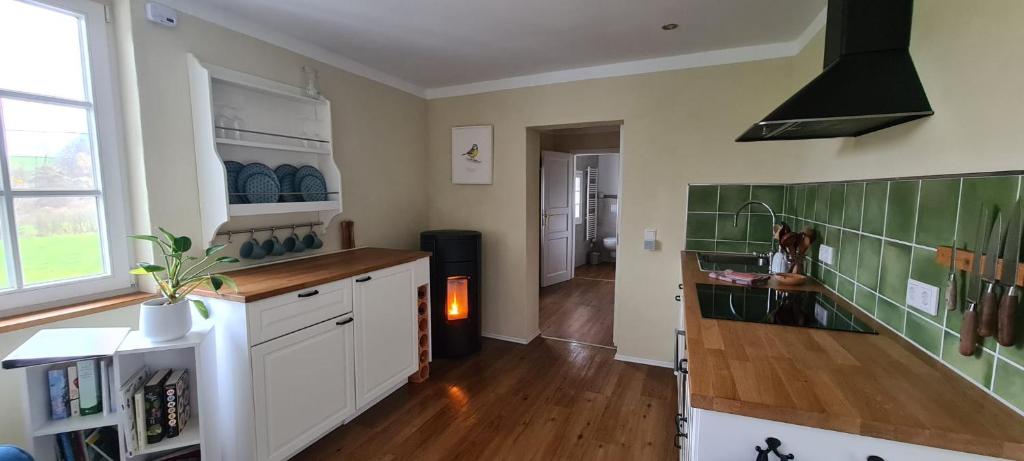 a kitchen with white cabinets and green tiles on the wall at Jedermanns Nest in Nümbrecht