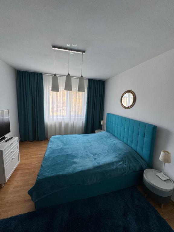 a bedroom with a blue bed and a television at Miri Apartament in Lupeni
