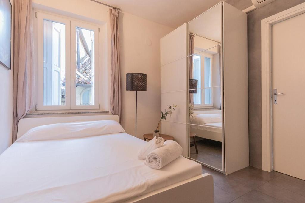a bedroom with a white bed and a large window at City Center - TinyStudio Piazza San Giacomo in Udine