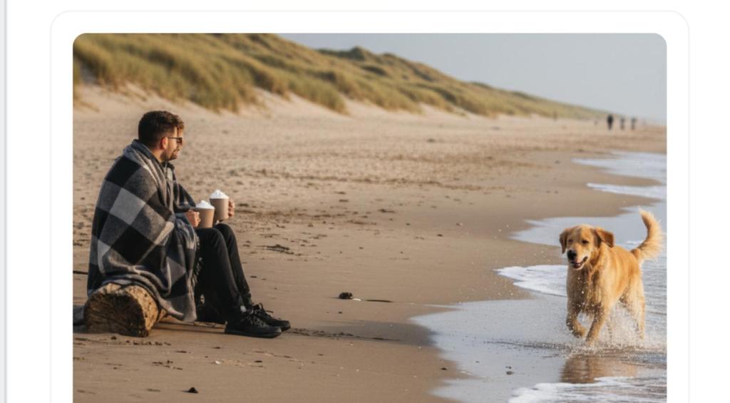 a man sitting on the beach next to a dog at Coastal Family Stay Zoutelande in Zoutelande