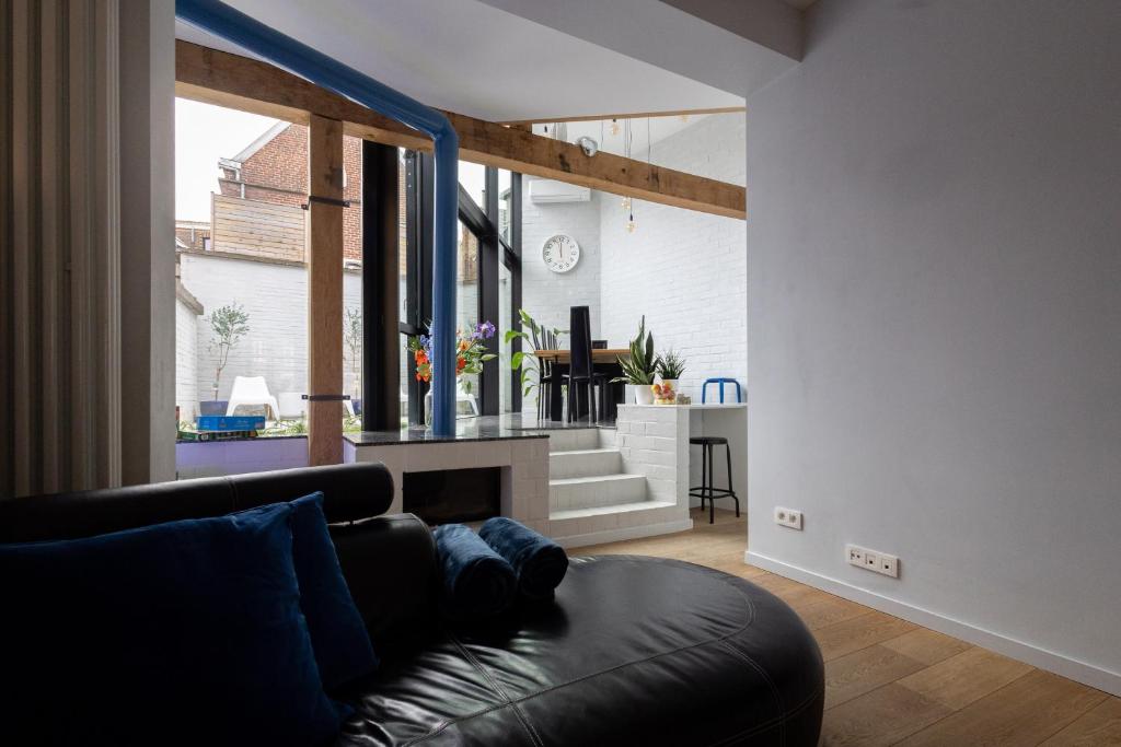 a living room with a black leather couch and a window at Townhouse Tongeren Center 275m2, 10p - Featured in Designbook in Tongeren