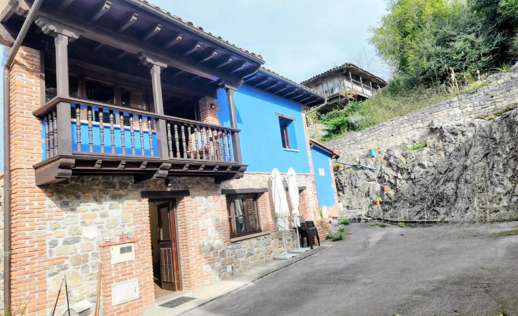 ein blaues Haus mit einem Balkon an einer Straße in der Unterkunft Casa vacacional El Rincón de Soto in Soto de Cangas
