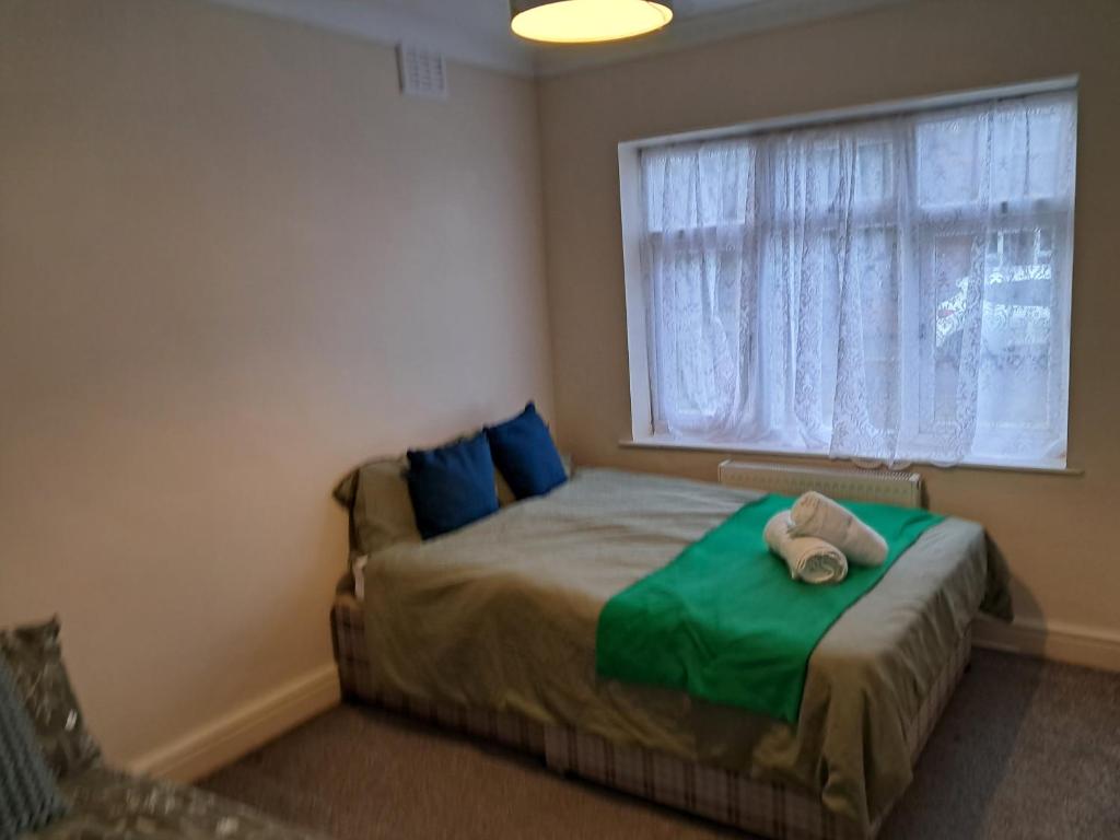 a bedroom with a bed with a green blanket and a window at Cosy 2 Bedroom Luxury House in Wednesbury