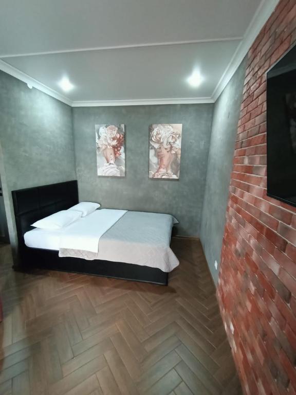 a bedroom with a bed and a brick wall at Квартира в центре города in Petropavlovsk