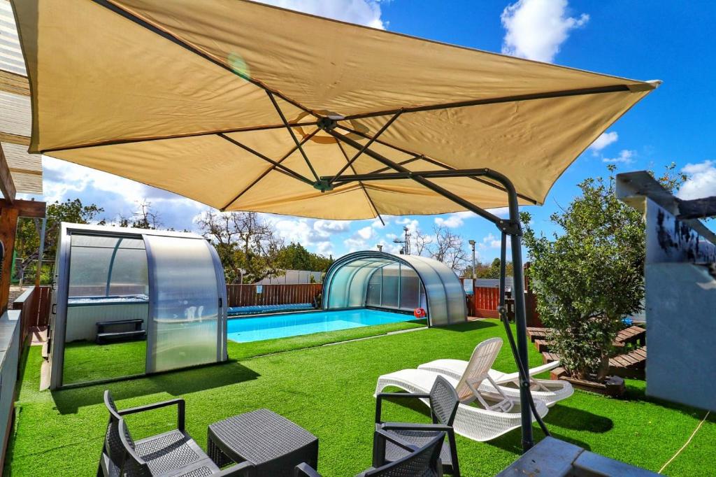 a large yellow umbrella in a backyard with a pool at אגם בגליל -וילה ו-3 סוויטות מקסימות למשפחות עם בריכה מחוממת in Wadi Keren