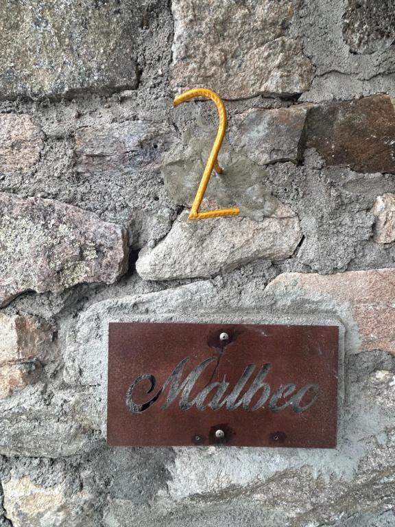 a metal sign on a stone wall at suites en la montaña con propuesta de viñedo in La Cumbre