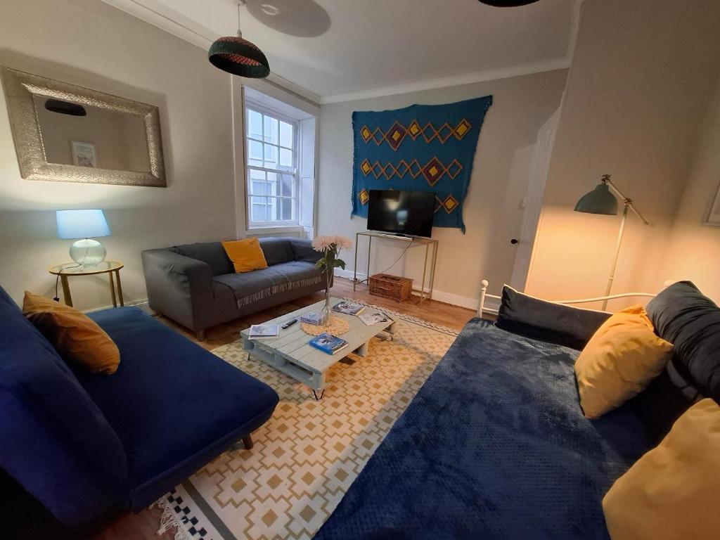 a living room with two couches and a table at 2 Courtyard Mews in Penzance