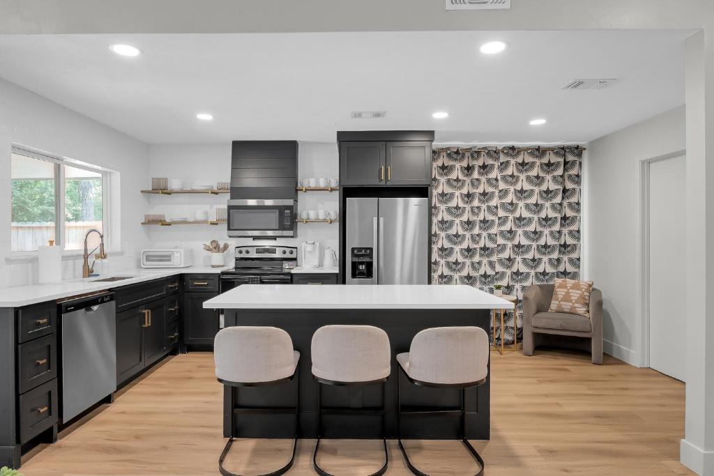 une cuisine avec des armoires noires et un îlot avec des tabourets de bar dans l'établissement Fire Pit Grill Hammock King Bed, à Spring