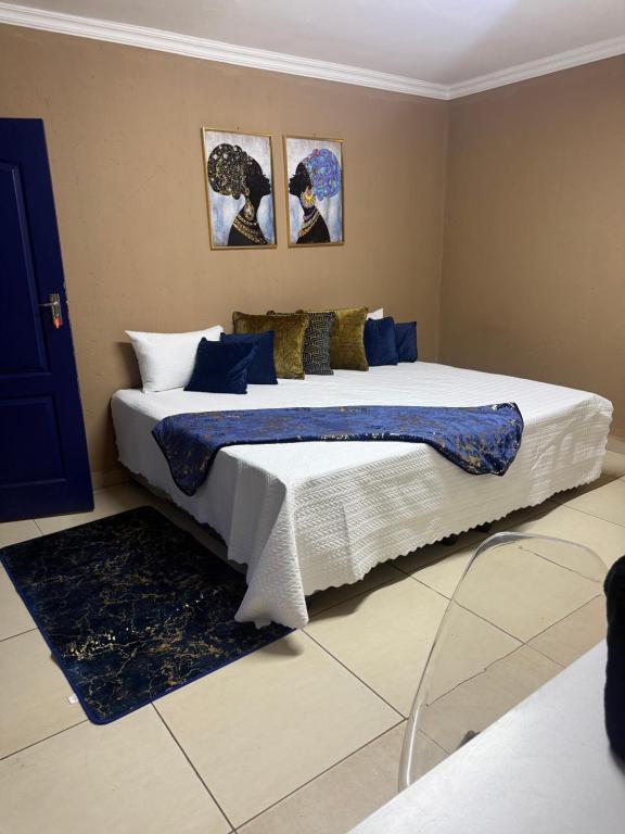 ein Schlafzimmer mit einem großen Bett mit blau-weißer Bettwäsche in der Unterkunft VinVid Harties Guest House in Hartbeespoort