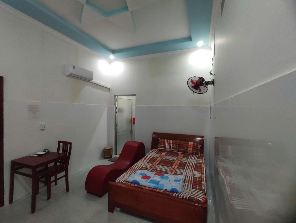 a bedroom with a bed and a chair and a table at Nhà nghỉ Đông Phương in Trung An