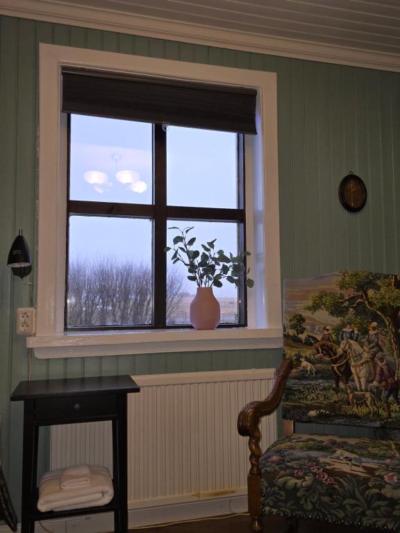 uma janela em uma sala com uma cadeira e um vaso em Prestshús 2 Guesthouse em Vík