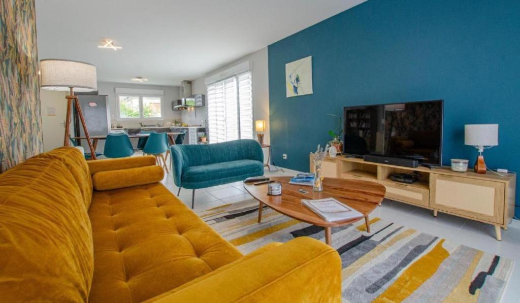 a living room with a yellow couch and a television at Le Fairway in Bréviandes