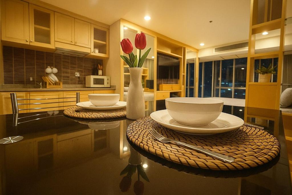 a kitchen with two tables and a vase with red flowers at Modern Suite near BTS Nana Netflix Sky View in Makkasan