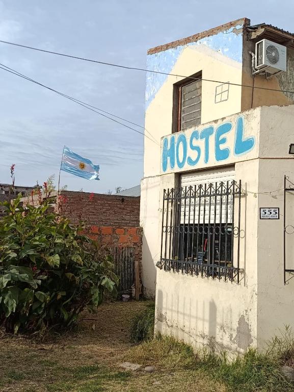 a building with a hostel sign and a flag at Hostel, La Casa del Patio in Bahía Blanca