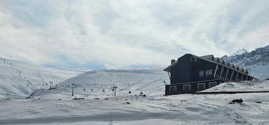 a building on a snowy hill with people in the snow at Kaf Mount Erciyes in Hacılar