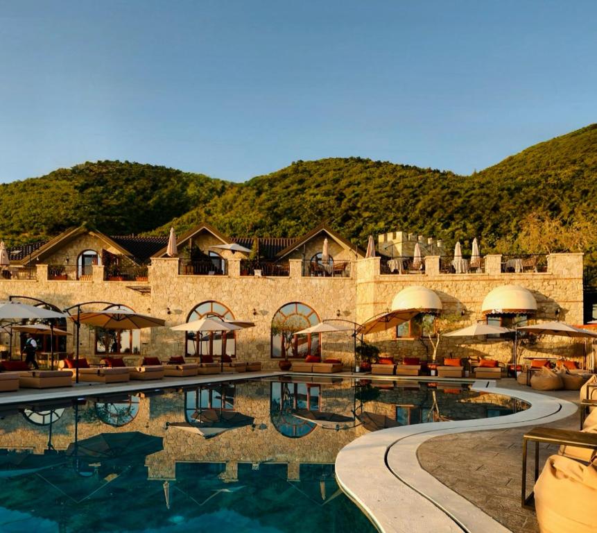 un complejo con una piscina con una montaña en el fondo en Chateau Fasel, en Tirana