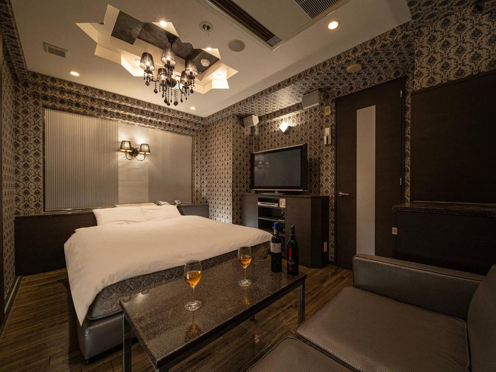 a bedroom with a bed and two glasses of wine at ホテルレジェンドプラス-Adult only in Kyoto