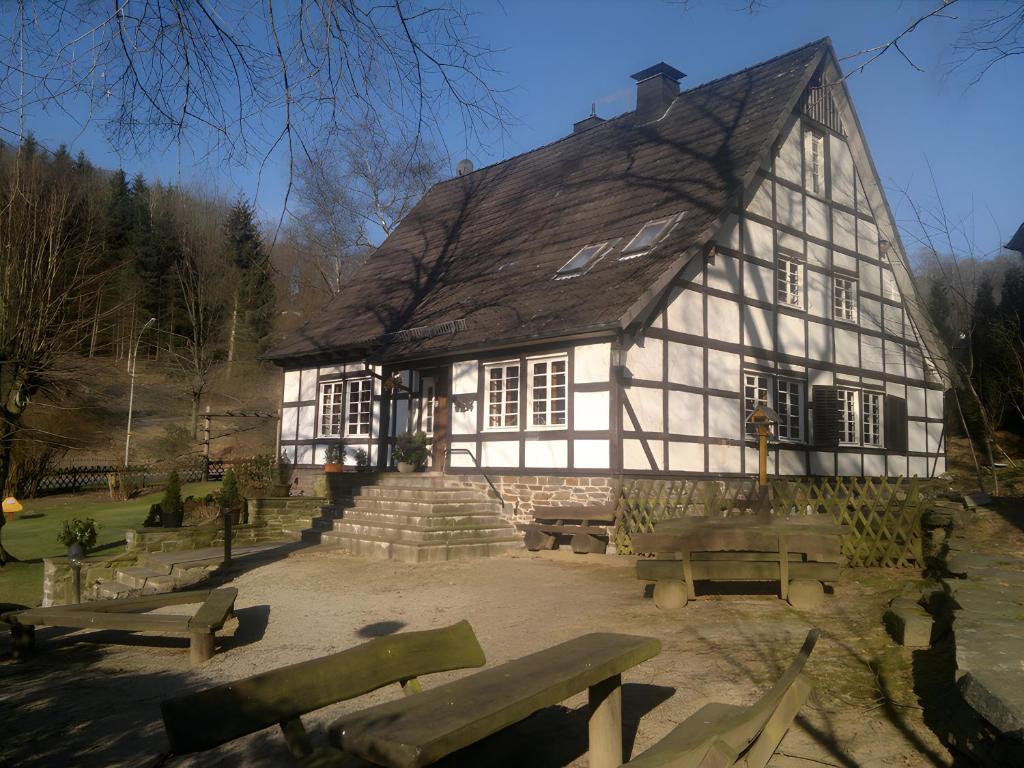 un vieux bâtiment blanc et noir avec bancs devant lui dans l'établissement Hueseken, à Finnentrop