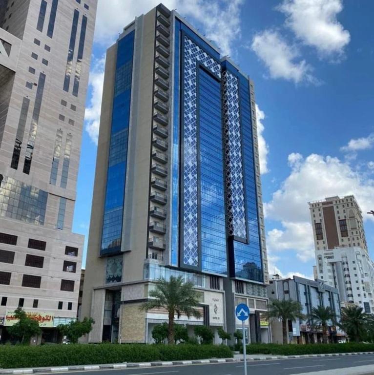 a tall building with blue windows on a city street at Hotel 21 Makkah in Mecca