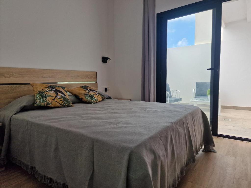 una camera da letto con un letto grande con una grande finestra di Hoy Cotillo Apartments a Cotillo