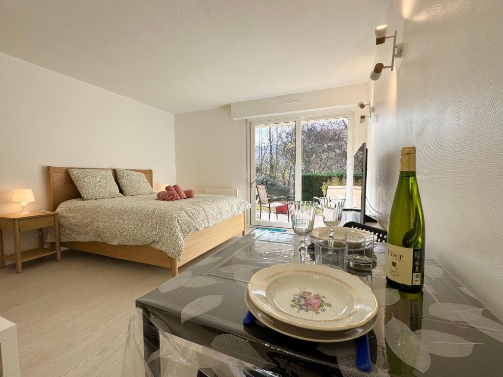 Zimmer mit einem Bett und einem Tisch mit einer Flasche Wein in der Unterkunft Le Nid des Frênes - Studio au Cœur de la Nature in Boersch