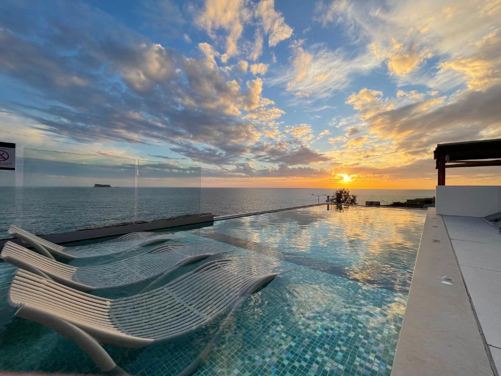 a pool with a lounge chair in front of the ocean at R Lapsi Guesthouse in Siġġiewi