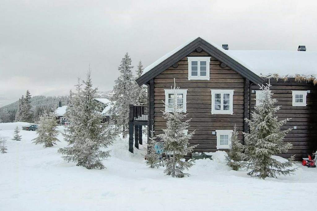 a log cabin in the snow with trees at Log Cabin By Mostertoppen Ski Stadium in Hafjell