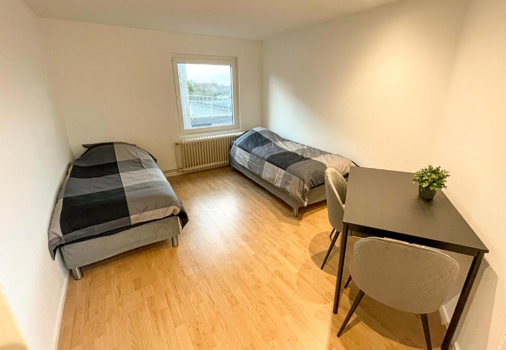 ein Zimmer mit zwei Betten und einem Schreibtisch und einem Tisch in der Unterkunft 44 - 5 Modern appartement voor 6 personen in Weener