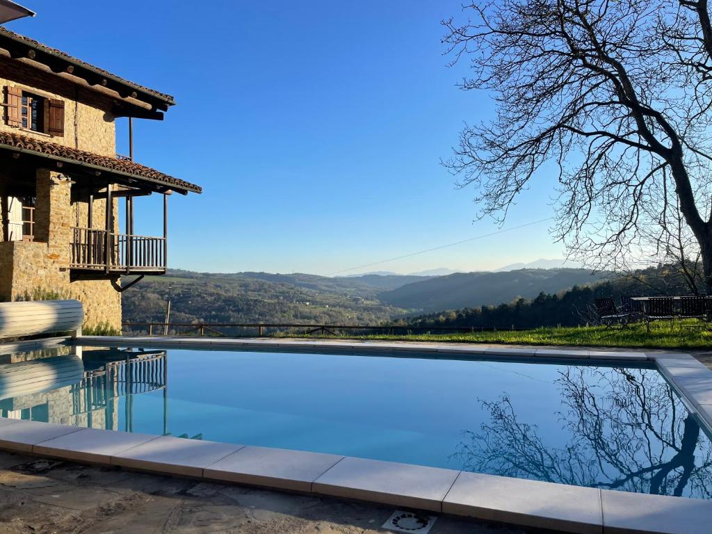 a swimming pool in front of a house with mountains in the background at Cascina Manzoni in Bossolasco